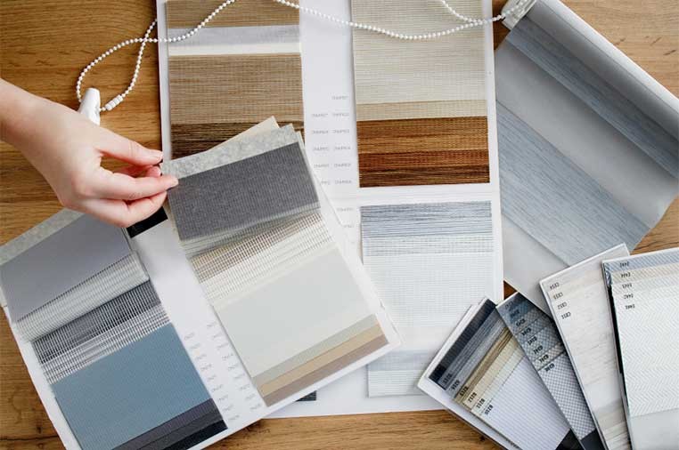 A hand sorting fabric swatches on a table
